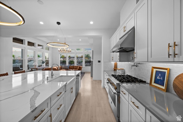 4771 W Juniper Bend Cir, Herriman, UT 84096 - kitchen with high end range, under cabinet range hood, a sink, recessed lighting, and light stone countertops
