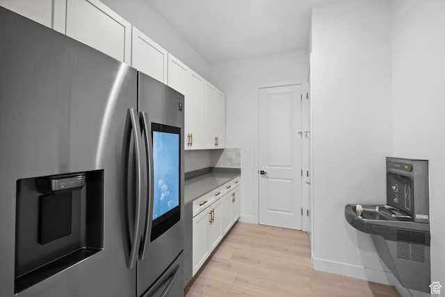 4771 W Juniper Bend Cir, Herriman, UT 84096 - kitchen featuring stainless steel refrigerator with ice dispenser, light wood-style flooring, white cabinets, and baseboards