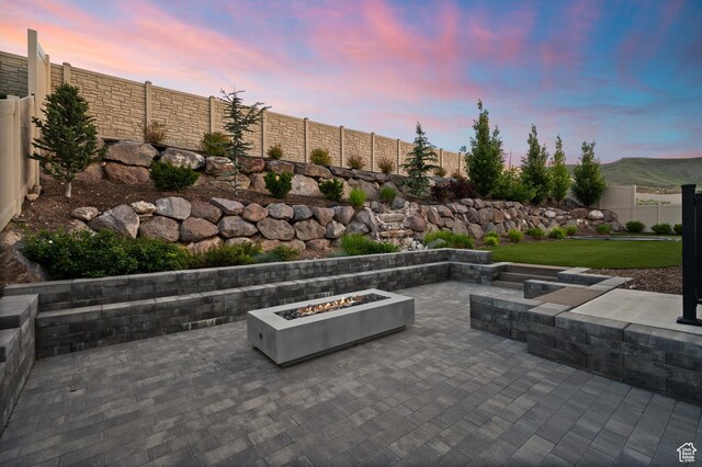 4771 W Juniper Bend Cir, Herriman, UT 84096 - patio terrace at dusk with a fire pit, a patio area, and a fenced backyard