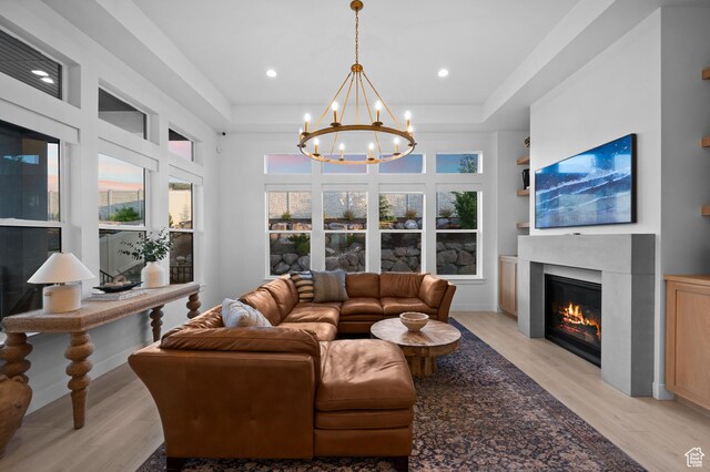 4771 W Juniper Bend Cir, Herriman, UT 84096 - living room with a glass covered fireplace, a tray ceiling, light wood finished floors, a chandelier, and recessed lighting