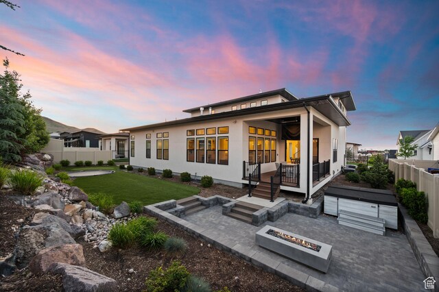4771 W Juniper Bend Cir, Herriman, UT 84096 - back of property at dusk with a patio, stucco siding, and a fire pit