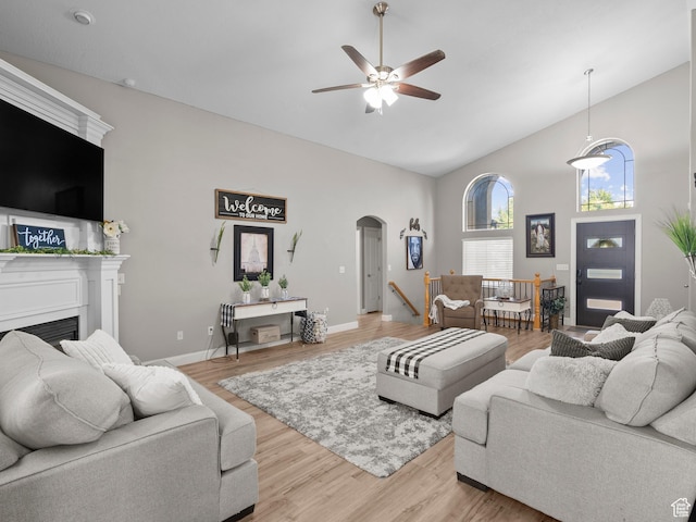 6121 W Indian Oak Dr S, West Jordan, UT 84081 - living area featuring high vaulted ceiling, arched walkways, a ceiling fan, light wood-style flooring, and a fireplace