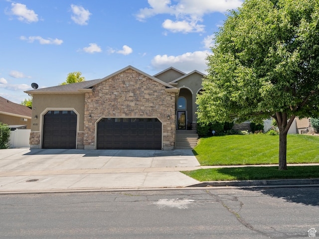 6121 W Indian Oak Dr S, West Jordan, UT 84081 - view of front of home with a front lawn, stucco siding, concrete driveway, a garage, and stone siding