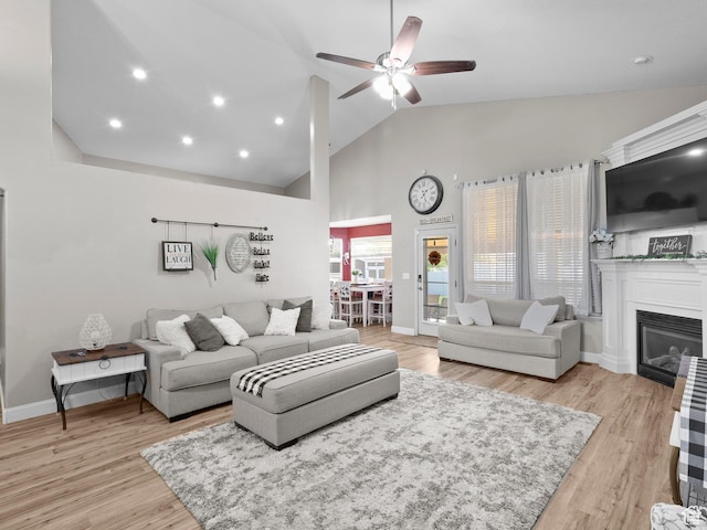 6121 W Indian Oak Dr S, West Jordan, UT 84081 - living room with ceiling fan, light wood-style flooring, high vaulted ceiling, a glass covered fireplace, and baseboards