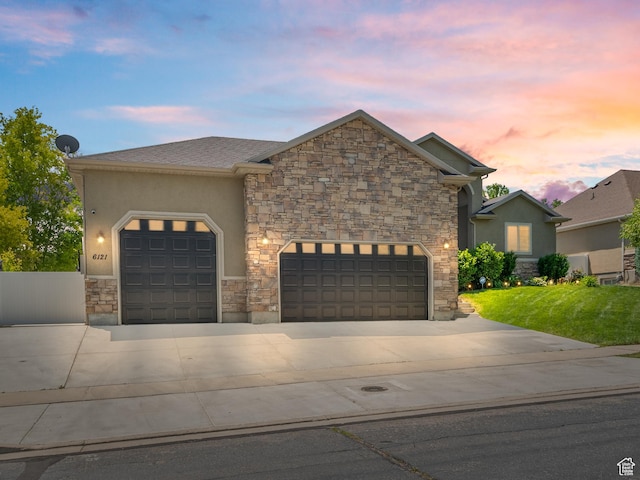 6121 W Indian Oak Dr S, West Jordan, UT 84081 - view of front facade with driveway, stone siding, a garage, stucco siding, and a front yard