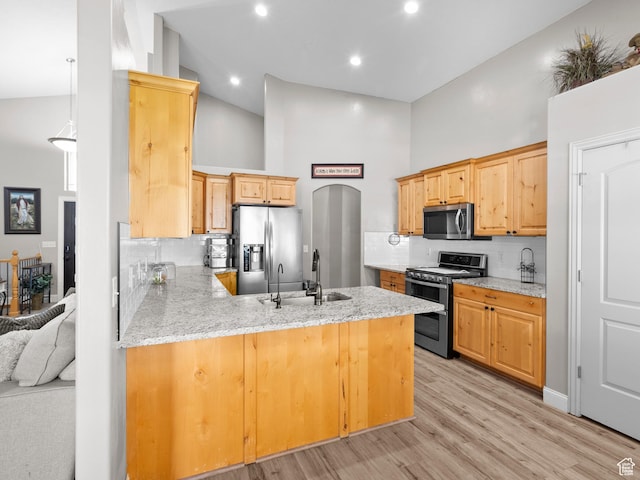 6121 W Indian Oak Dr S, West Jordan, UT 84081 - kitchen with appliances with stainless steel finishes, a high ceiling, a peninsula, decorative backsplash, and light wood finished floors