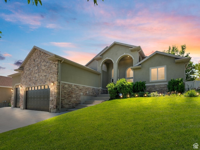 6121 W Indian Oak Dr S, West Jordan, UT 84081 - view of front of house with stone siding, a yard, stucco siding, and concrete driveway