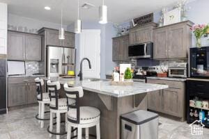 3454 W 150th St N, Hurricane, UT 84737 - kitchen featuring stainless steel appliances, a breakfast bar, tasteful backsplash, decorative light fixtures, and a kitchen island with sink