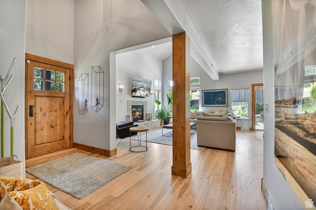 7841 Engen Loop, Park City, UT 84098 - foyer entrance featuring a stone fireplace, light wood-style floors, baseboards, a textured ceiling, and high vaulted ceiling