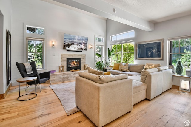 7841 Engen Loop, Park City, UT 84098 - living area featuring light wood-type flooring, a stone fireplace, a towering ceiling, and a textured ceiling