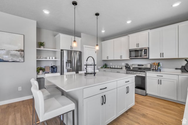 4185 W 800 S, Syracuse, UT 84075 - kitchen featuring appliances with stainless steel finishes, open shelves, white cabinetry, decorative light fixtures, and an island with sink