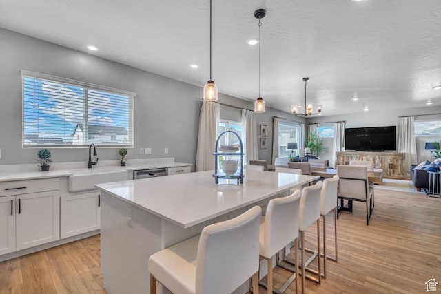 4185 W 800 S, Syracuse, UT 84075 - kitchen featuring a sink, a center island, light wood-style flooring, light countertops, and a breakfast bar area