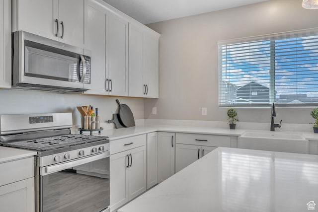 4185 W 800 S, Syracuse, UT 84075 - kitchen featuring stainless steel appliances, a sink, white cabinets, and wood finished floors