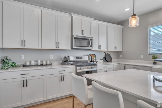 4185 W 800 S, Syracuse, UT 84075 - kitchen featuring appliances with stainless steel finishes, light countertops, white cabinetry, pendant lighting, and light wood-style floors
