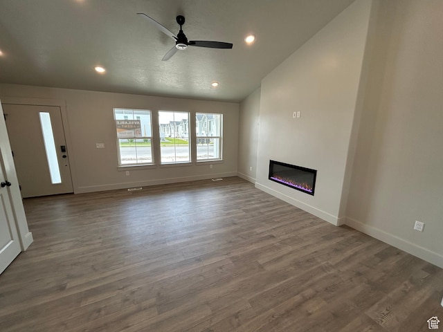 570 N 600 W, Smithfield, UT 84335 - unfurnished living room featuring baseboards, wood finished floors, a glass covered fireplace, recessed lighting, and vaulted ceiling