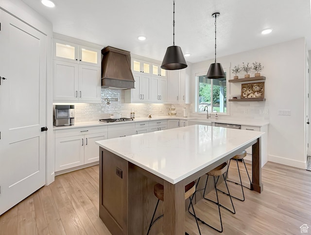 2558 N 1150 E, North Ogden, UT 84414 - kitchen featuring custom exhaust hood, light wood finished floors, a sink, decorative backsplash, and a breakfast bar area