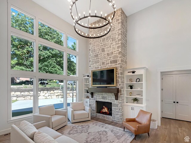 2558 N 1150 E, North Ogden, UT 84414 - living area with a towering ceiling, wood finished floors, a chandelier, a stone fireplace, and baseboards