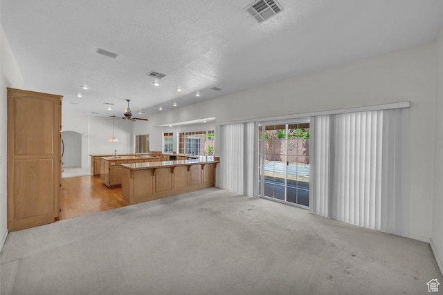 3350 S Fairway Rd, St George, UT 84790 - kitchen with a textured ceiling, light colored carpet, a ceiling fan, a kitchen breakfast bar, and decorative light fixtures