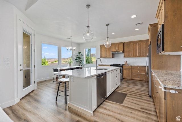 1432 Boys Pond Cir, Santa Clara, UT 84765 - kitchen featuring appliances with stainless steel finishes, brown cabinetry, light wood-style floors, a kitchen island with sink, and recessed lighting