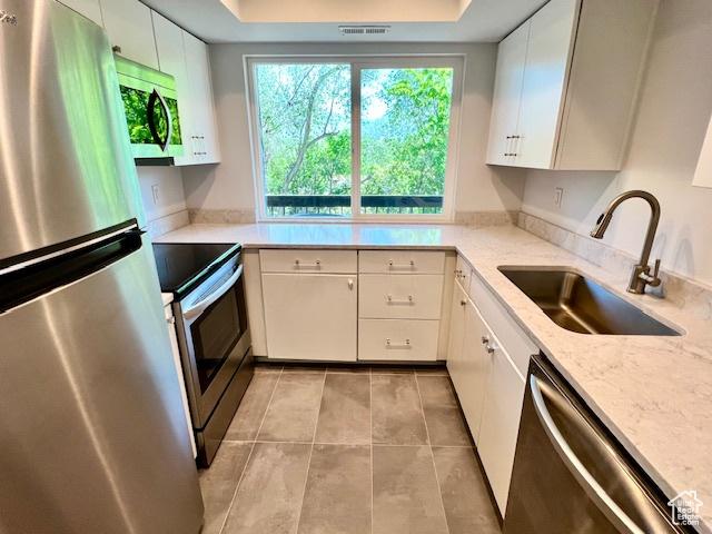 4969 S Eastridge Ln E Unit 174, Salt Lake City, UT 84117 - kitchen featuring stainless steel appliances, a sink, a raised ceiling, light tile patterned floors, and white cabinets