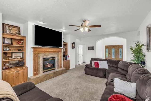 1165 W Indian Hills Dr Unit 236, St George, UT 84770 - carpeted living room featuring arched walkways, a fireplace, a ceiling fan, and a textured ceiling