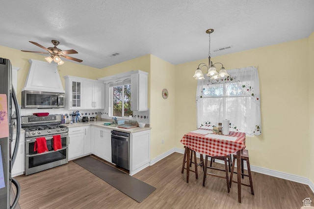 1165 W Indian Hills Dr Unit 236, St George, UT 84770 - kitchen featuring appliances with stainless steel finishes, wood finished floors, white cabinetry, light countertops, and a chandelier