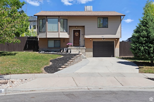 5063 W Milstead Ln, Kearns, UT 84118 - split foyer home featuring brick siding, concrete driveway, an attached garage, and a chimney