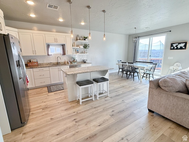 5893 S Kastra Ln, St George, UT 84790 - kitchen featuring stainless steel appliances, white cabinetry, light stone countertops, open floor plan, and backsplash