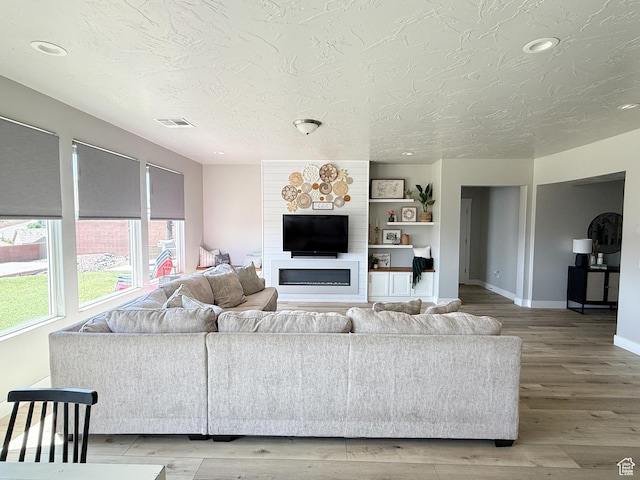 5893 S Kastra Ln, St George, UT 84790 - living room with a textured ceiling, light wood finished floors, a glass covered fireplace, and recessed lighting