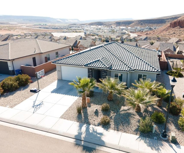 5893 S Kastra Ln, St George, UT 84790 - view of front of house featuring a garage, driveway, a tiled roof, a residential view, and stucco siding