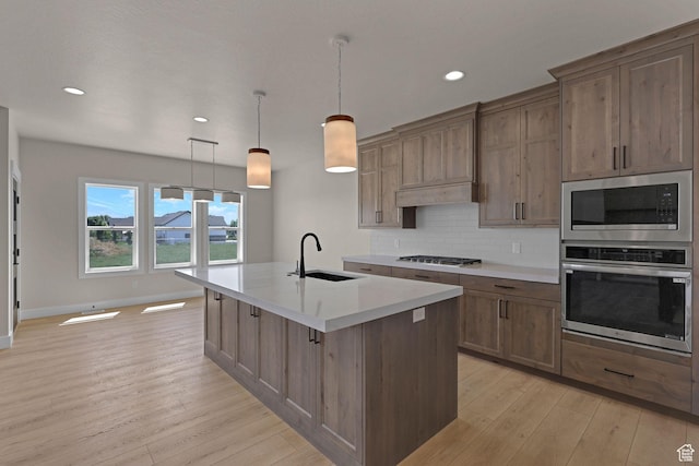 4594 S 6300 W, Hooper, UT 84315 - kitchen with stainless steel appliances, a sink, light wood-style floors, light countertops, and a center island with sink