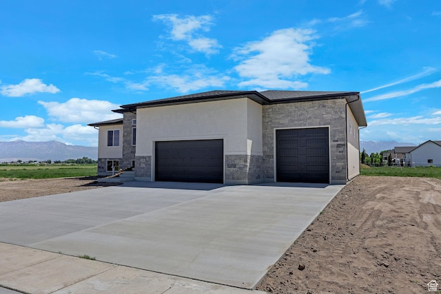 4594 S 6300 W, Hooper, UT 84315 - view of side of home with stone siding, a mountain view, driveway, a garage, and stucco siding