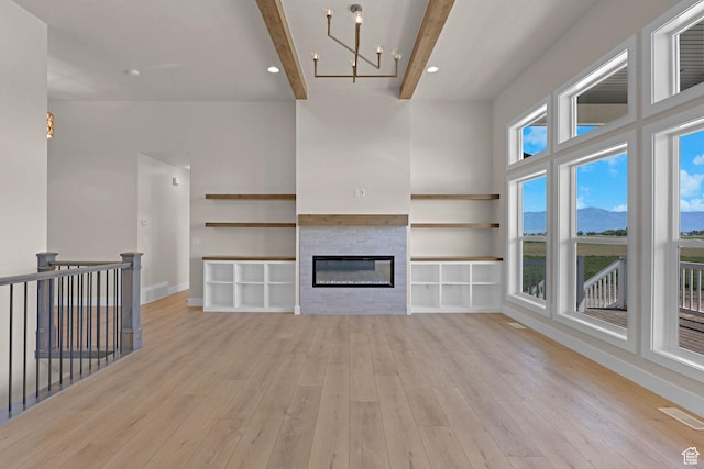 4594 S 6300 W, Hooper, UT 84315 - unfurnished living room with beamed ceiling, light wood-style flooring, a glass covered fireplace, a chandelier, and baseboards