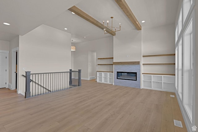 4594 S 6300 W, Hooper, UT 84315 - unfurnished living room featuring light wood-style flooring, beamed ceiling, recessed lighting, a chandelier, and a glass covered fireplace
