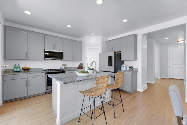 1815 E Thunder Gulch Rd, Eagle Mountain, UT 84005 - kitchen featuring stainless steel gas range oven, gray cabinetry, fridge with ice dispenser, light wood-type flooring, and recessed lighting