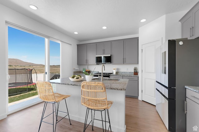 1815 E Thunder Gulch Rd, Eagle Mountain, UT 84005 - kitchen with stainless steel appliances, gray cabinetry, light stone counters, an island with sink, and recessed lighting