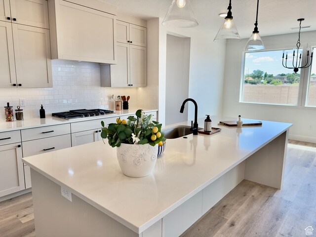 525 N 3380 W Unit 16, Hurricane, UT 84737 - kitchen with a sink, light wood-type flooring, tasteful backsplash, and a center island with sink