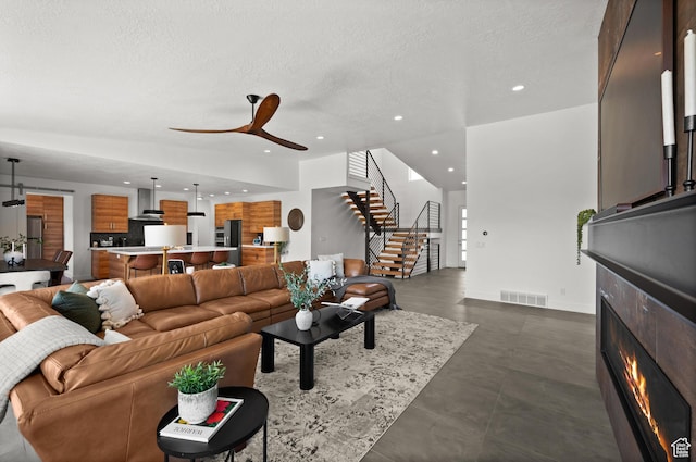 507 W Windmill Gate Cv, Draper, UT 84020 - living room featuring recessed lighting, stairway, a warm lit fireplace, a ceiling fan, and a textured ceiling