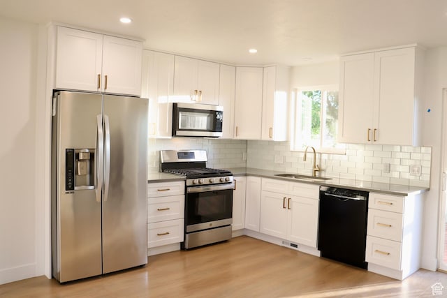 579 N 430 E Unit 2, Tooele, UT 84074 - kitchen featuring stainless steel appliances, a sink, white cabinets, decorative backsplash, and light wood-style flooring