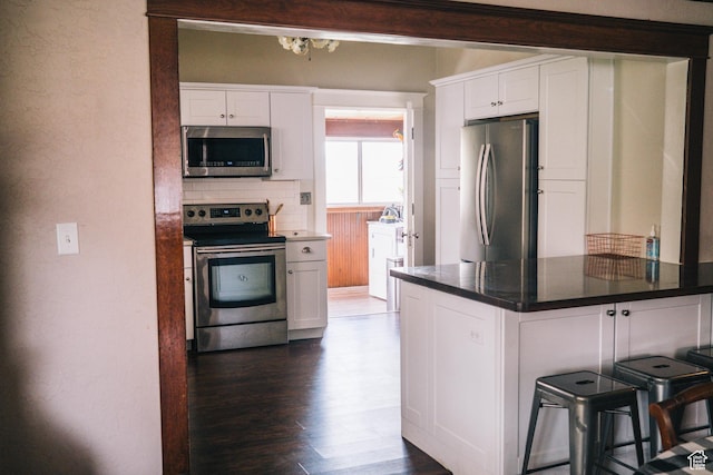 201 Bannock St, Malad City, ID 83252 - kitchen featuring appliances with stainless steel finishes, white cabinetry, a kitchen bar, and dark countertops