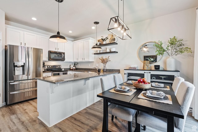 819 E 12085 S, Draper, UT 84020 - kitchen featuring appliances with stainless steel finishes, a peninsula, light wood-style flooring, white cabinets, and dark stone counters