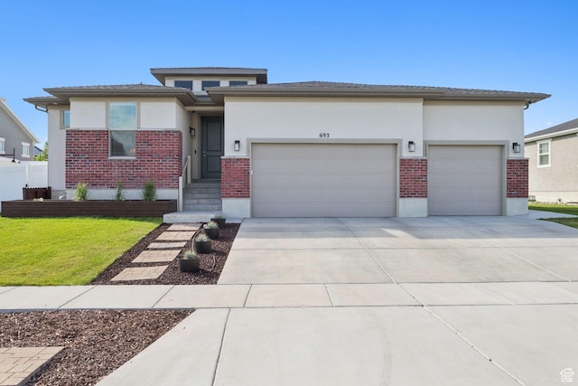 693 W Fireside Ln, Stansbury Park, UT 84074 - prairie-style house featuring brick siding, an attached garage, and stucco siding