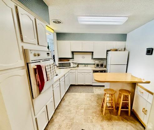 381 W 400 N Unit 12, Bountiful, UT 84010 - kitchen featuring white appliances, light countertops, a kitchen bar, white cabinets, and a sink