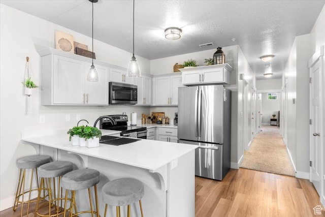 4192 W Mckellen Dr Unit B2, Herriman, UT 84096 - kitchen featuring appliances with stainless steel finishes, a peninsula, light countertops, a breakfast bar area, and light wood finished floors