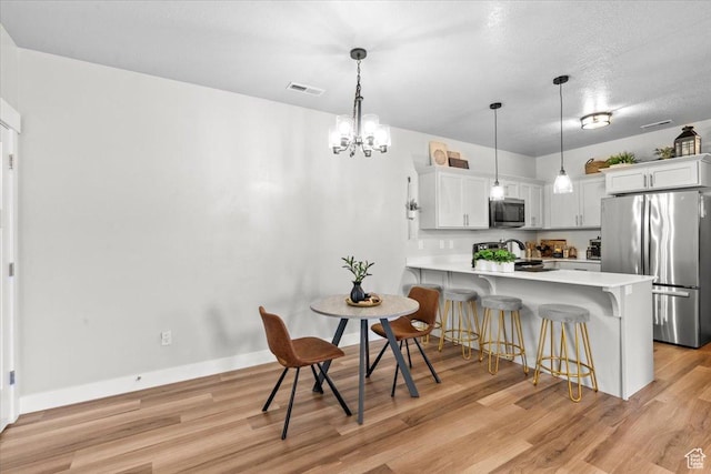 4192 W Mckellen Dr Unit B2, Herriman, UT 84096 - kitchen featuring stainless steel appliances, light countertops, a kitchen bar, a peninsula, and light wood-type flooring
