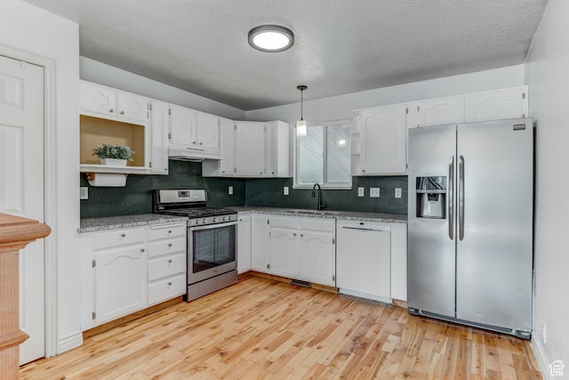 4799 S 3900 W, Roy, UT 84067 - kitchen with stainless steel appliances, white cabinetry, tasteful backsplash, light wood-style floors, and under cabinet range hood