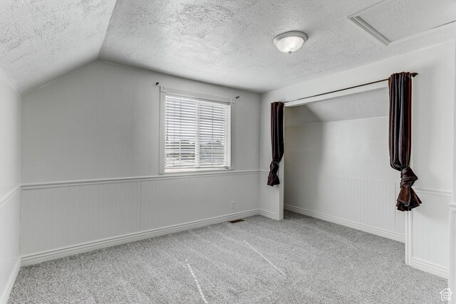 4799 S 3900 W, Roy, UT 84067 - unfurnished bedroom featuring a textured ceiling, carpet floors, vaulted ceiling, a wainscoted wall, and attic access