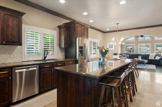 4280 S Scenic Cir E, Bountiful, UT 84010 - kitchen featuring appliances with stainless steel finishes, a sink, open floor plan, crown molding, and dark stone counters