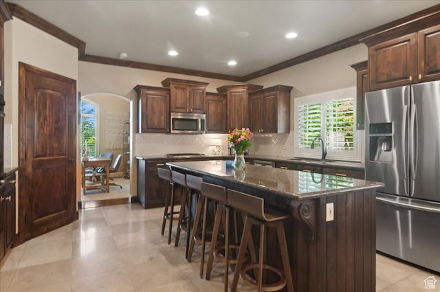 4280 S Scenic Cir E, Bountiful, UT 84010 - kitchen with stainless steel appliances, ornamental molding, a sink, arched walkways, and a kitchen breakfast bar