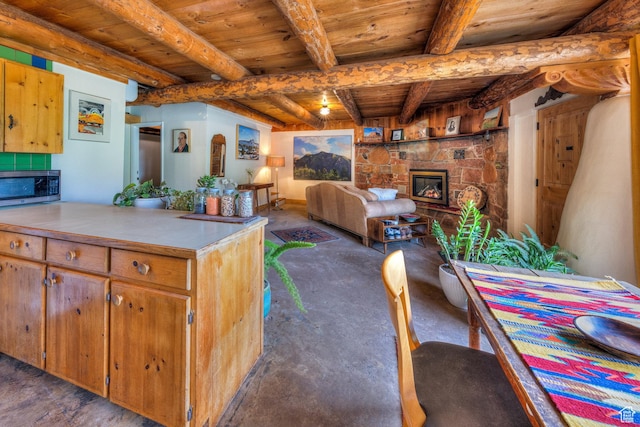 7020 E Creekside Ln, Castle Valley, UT 84532 - kitchen featuring a fireplace, wood ceiling with exposed beams, stainless steel microwave, light countertops, and unfinished concrete floors